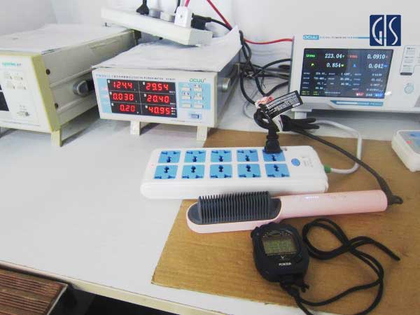GIS Inspection inspector performing a power consumption test on a hair straightening brush during a safety inspection at a factory in China