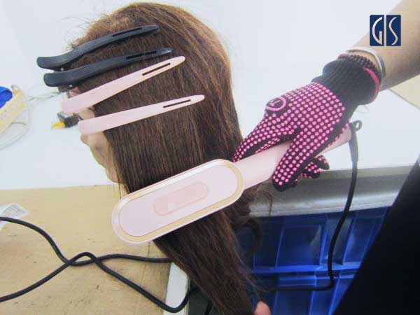 GIS Inspection inspector performing a functional test on an Amazon FBA hair straightening brush during a quality inspection at a factory in China
