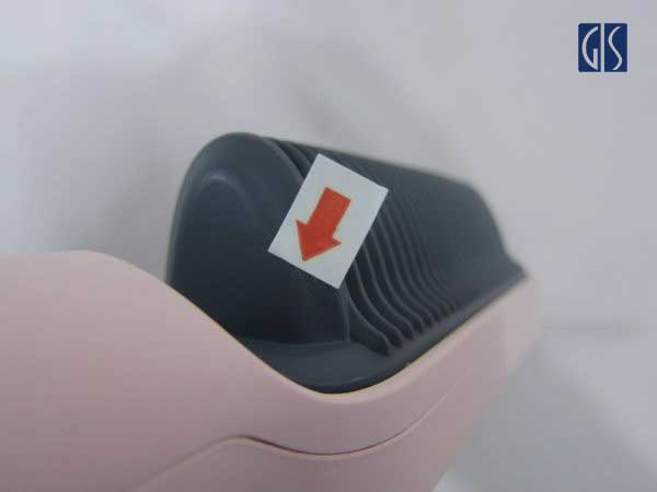 Close-up of a black electric hair straightener brush handle showing a distinct 2-centimeter surface scratch on the matte plastic casing.